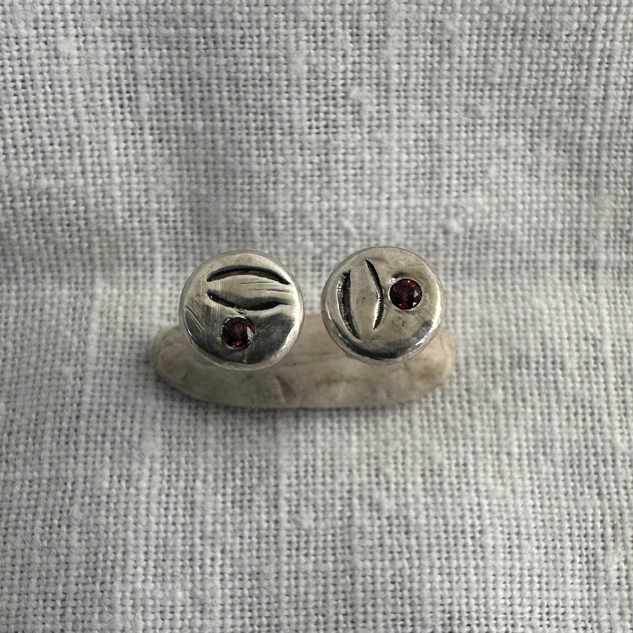 "Détail des boucles d'oreilles puce Bintou - scarifications oxydées et serti masse grenat"